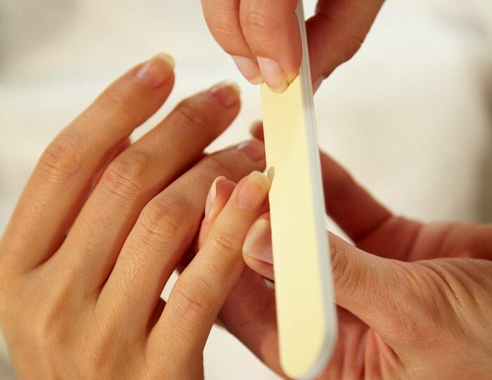 Two hands carefully file fingernails during a manicure in the Kristall Spa.