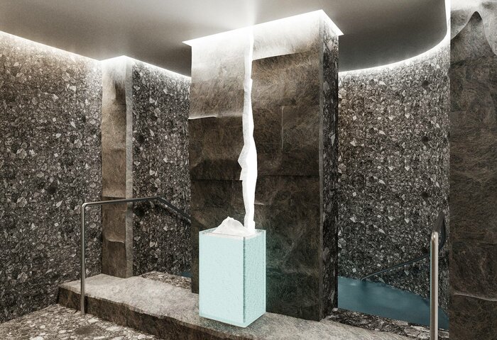 Ein moderner Wellnessbereich mit dunklen Steinwänden und einem zentralen Wasserfall, der aus einem hellen Block fließt. Stufen führen zu einem kleinen Wasserbecken, während sanftes Licht von der Decke strahlt und eine entspannende Atmosphäre schafft.