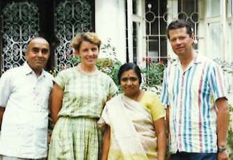 Four people from the Leeb and Klein host family stand in front of a building with windows and grilles.