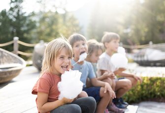 Mehrere Kinder sitzen draußen und essen Zuckerwatte im Familienurlaub im Hotel Hochschober.