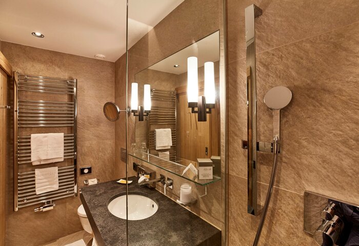 Bathroom with vanity in single room A bathroom with vanity, large mirror, heated towel rail and shower in a single room.