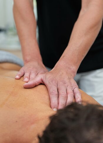 Ein Masseur behandelt den Rücken einer liegenden Person mit beiden Händen im Kristall Spa.