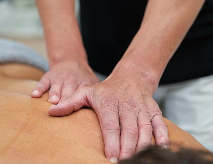 A therapist massages the back of a reclining person with both hands in the Kristall Spa.