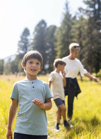 Eine Familie mit Kindern und Oma wandert im Herbst durch eine sonnige Wald- und Berglandschaft auf der Turracher Höhe.