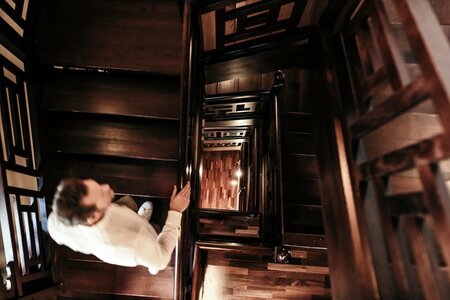 Eine Person steigt eine dunkle Holz-Spindeltreppe im Innenbereich hinab.