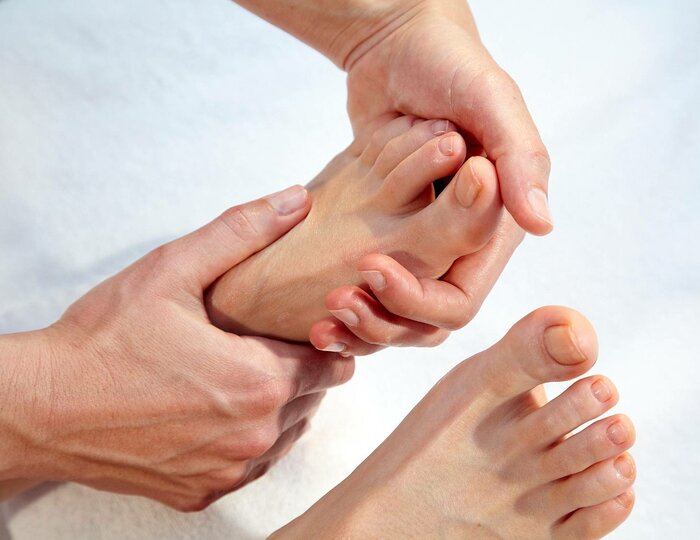 A therapist performs foot reflexology massage on a guest's sole in the Kristall Spa.