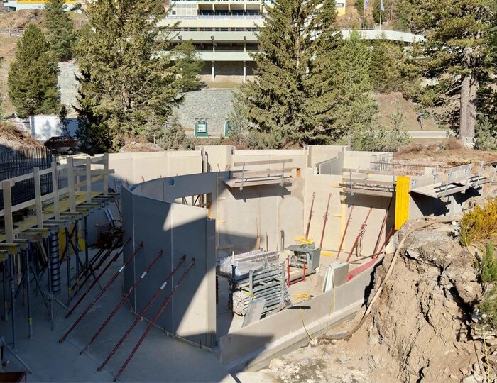 Auf der Baustelle des Hotel Hochschober ist ein großer Betonbau mit Gerüsten, Schalung und Materiallager zu sehen.