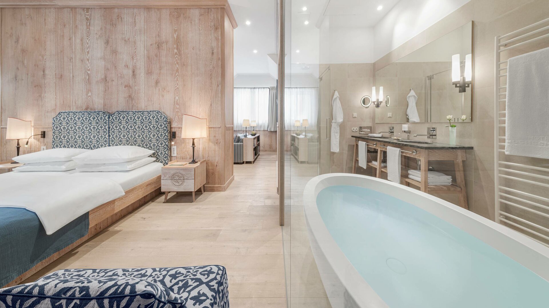 The Bergkristall Suite shows a bedroom with a bench and a bathroom with a freestanding bathtub.