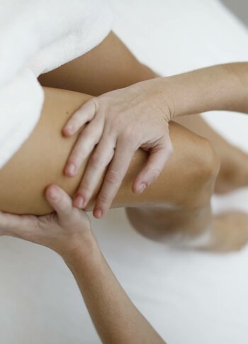 Eine Therapeutin führt eine Lymphdrainage am Bein einer liegenden Person im Kristall Spa durch.