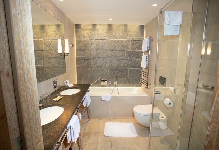 Blick in das Bad eines Superior Doppelzimmers im Stammhaus mit Doppelwaschtisch, Badewanne und Glasdusche.