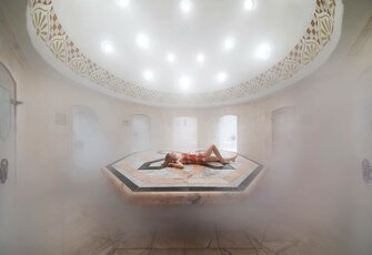 Eine Person liegt entspannt auf der beheizten Liege im dampfigen Hamam des Hotel Hochschober.