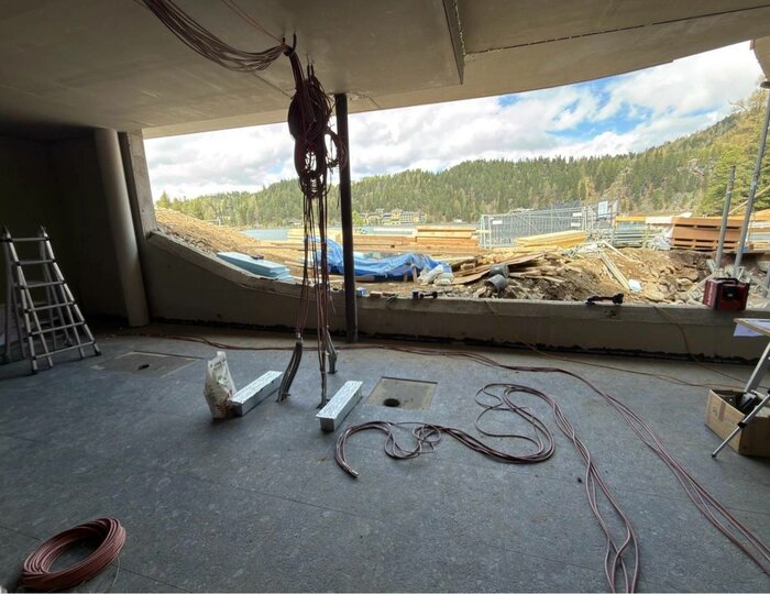 Umbau Hotel Hochschober: Seeblick-Baustelle Im Innenraum einer Baustelle öffnet sich ein großer Durchbruch mit Blick auf den See und das Waldufer.