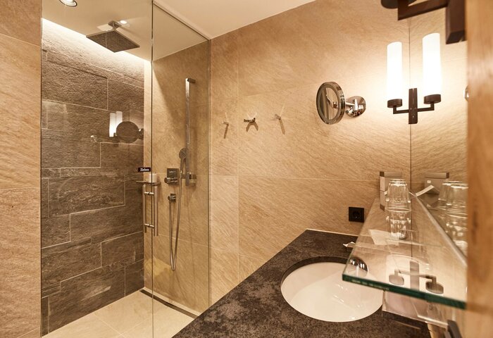 Classic Studio bathroom with glass shower An elegant bathroom in the Classic Studio with a glass shower, light stone surfaces, black counter and basin.