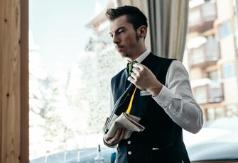 Ein Hotelmitarbeiter hält eine Mappe und einen Zimmerschlüssel an der Rezeption.