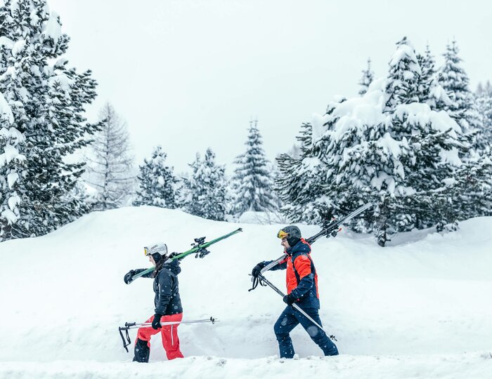 Skiers in deep snow on Turracher Höhe Two skiers walk through fresh deep snow between snow-covered fir trees on Turracher Höhe.