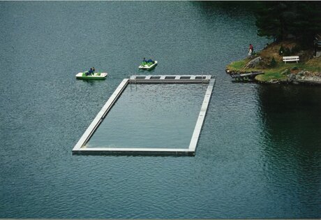 A heated lake pool sits in the Turracher See, with two small pedal boats nearby on the water.