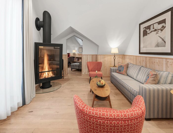Wohnzimmer mit Kamin in einer Hotelsuite Ein gemütliches Wohnzimmer in einer Hotelsuite mit Kamin, Sofa, Sessel und hellem Holzboden.