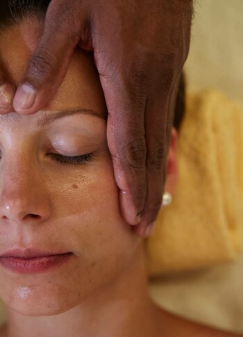 Eine Person erhält eine Shiro-Padabhyanga-Behandlung mit sanfter Kopfmassage im Kristall Spa.