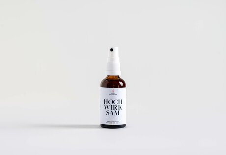 A small brown spray bottle with a white label stands against a light background.