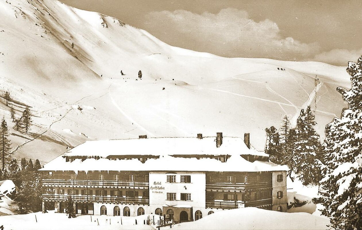 The historic Hotel Hochschober stands deeply covered in snow against the winter landscape of Turracher Höhe.