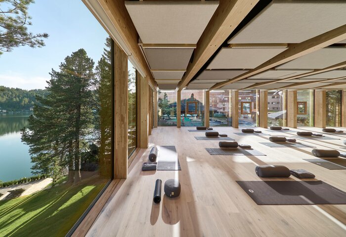 Ein heller Yoga-Raum mit Matten und Yogarollen mit Blick auf den See und die umliegende Natur.