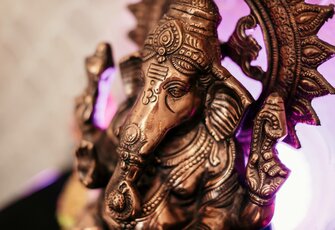 Eine bronzene Ganesha-Figur ist im sanft beleuchteten Spa-Bereich des Hotel Hochschober zu sehen.