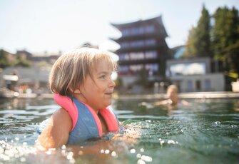 Ein Kind schwimmt mit Schwimmhilfe im See-Bad vor dem Hotel Hochschober.