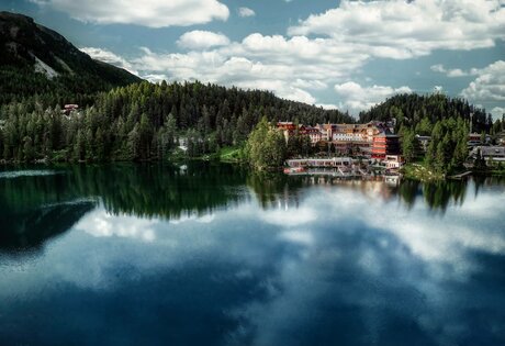 Hotel Hochschober stands on the shore of Turracher See, surrounded by forest, mountains and calm water.