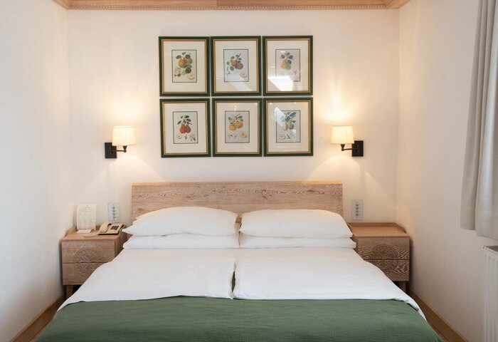 Classic double room in the Stammhaus of Hotel Hochschober A tidy classic double room with a double bed, bedside tables, wall art and a side window view.