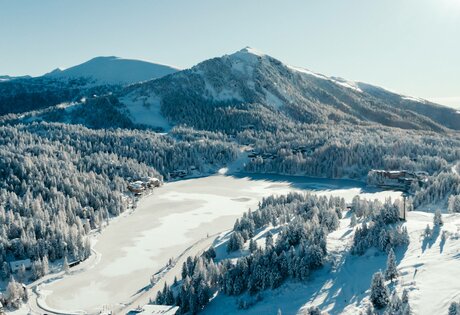 Snow-covered slopes and a frozen lake lie beneath the mountain panorama on the Turracher Höhe.