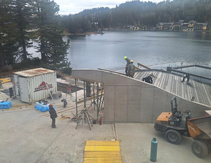 Baustelle am See-Bad des Hotel Hochschober Am Ufer des Sees entsteht ein See-Bad; Bauarbeiter und ein Bagger arbeiten an der Holz- und Stahlkonstruktion.