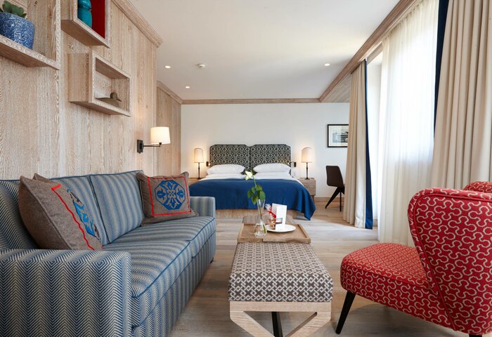 Deluxe Bergkristall Room at Hotel Hochschober The Deluxe Bergkristall room shows a seating area with sofa, table and chair, plus a bed with a padded headboard.