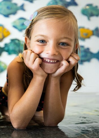 A smiling girl lies on a water surface in the wellness area.