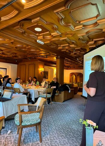 Vortrag im Hotelrestaurant des Hotel Hochschober Eine Frau hält einen Vortrag vor sitzenden Gästen in einem holzgetäfelten Raum mit gedeckten Tischen.