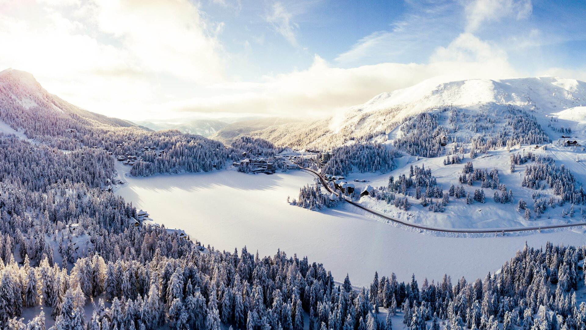 Blick über den verschneiten See und die winterlichen Berge an der Turracher Höhe.