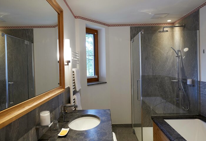 Bathroom in the Deluxe Swiss Pine Room Bathroom in the Deluxe Swiss Pine Room with a vanity, mirror and glass shower.