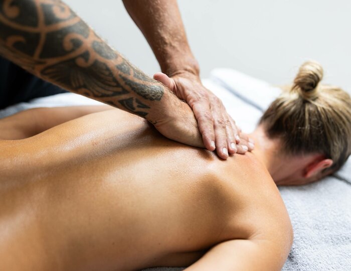 Haki Purna Massage im Kristall Spa Eine Frau liegt mit dem Gesicht nach unten auf der Massageliege, während der Therapeut ihren Rücken mit den Händen behandelt.