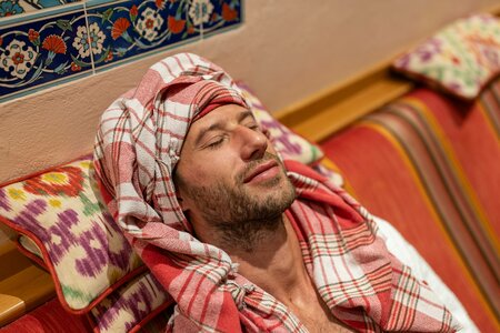 Ein Mann sitzt entspannt mit Handtuch auf einer Liege im Hamam des Hotel Hochschober.