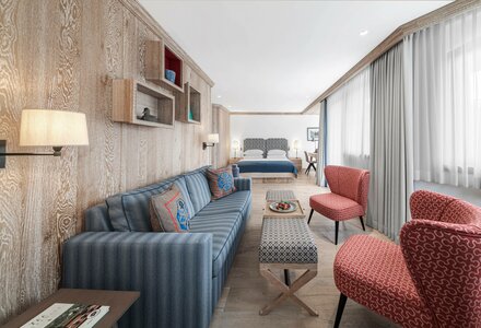 Eine helle Suite mit Sofa, Sesseln, Bett und großflächigen Fensterfronten im Hotel Hochschober.