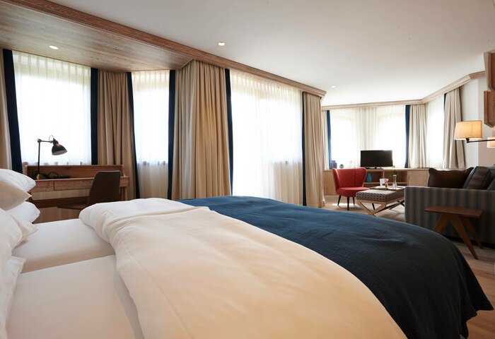 Bergkristall Apartment at Hotel Hochschober A bright hotel apartment with a double bed, sofa, armchair and large windows with curtains.