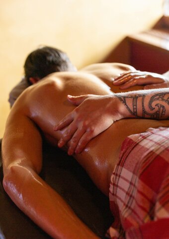 Eine Person erhält eine entspannende Massage im Kristall Spa, während die Hände der Therapeutin den Rücken behandeln.