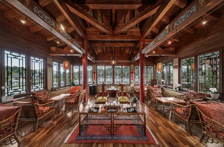 Ein holzverkleideter Lounge-Raum mit Sitzgruppen, Tischen und großen Fenstern im Chinaturm.