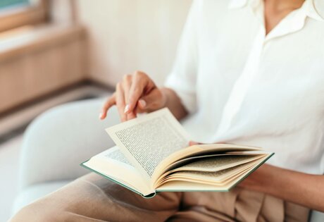 Eine Person liest entspannt in einem aufgeschlagenen Buch in der Bibliothek Wortreich des Hotel Hochschober.