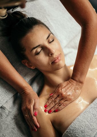 Eine Frau erhält im Kristall Spa des Hotel Hochschober eine entspannende Massage mit Öl auf Kopf und Schultern.