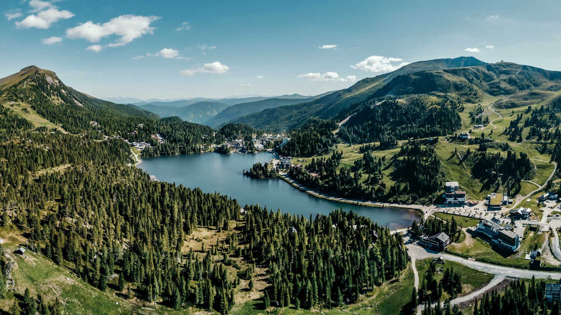 Blick über den Turracher See mit Wäldern, Almen und Bergen in den Nockbergen.