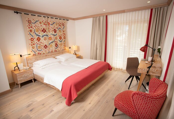 A bright family apartment with a double bed, desk, armchair and large windows at Hotel Hochschober.