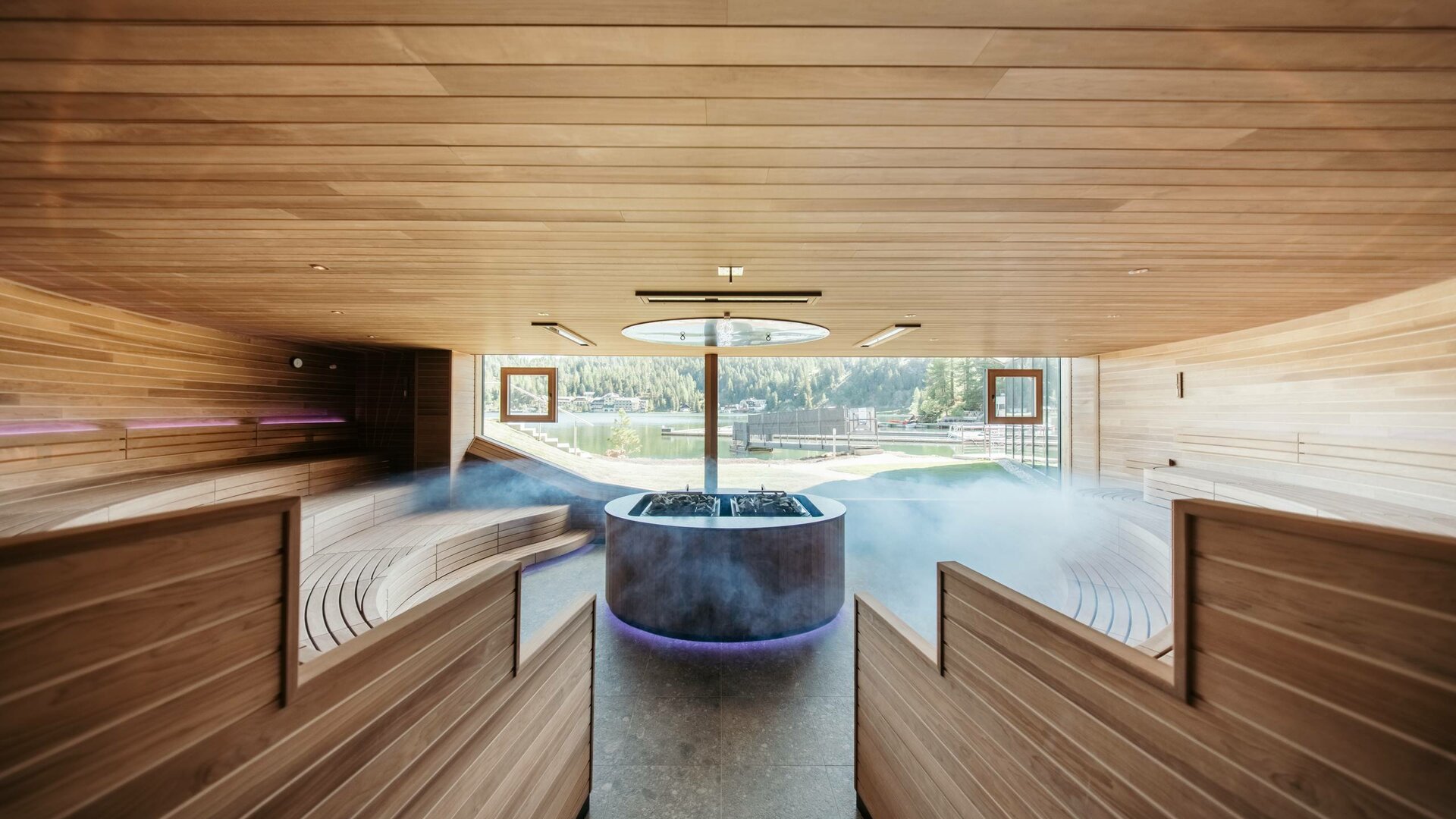 An indoor infinity pool with wood paneling and a lake view at Hotel Hochschober.