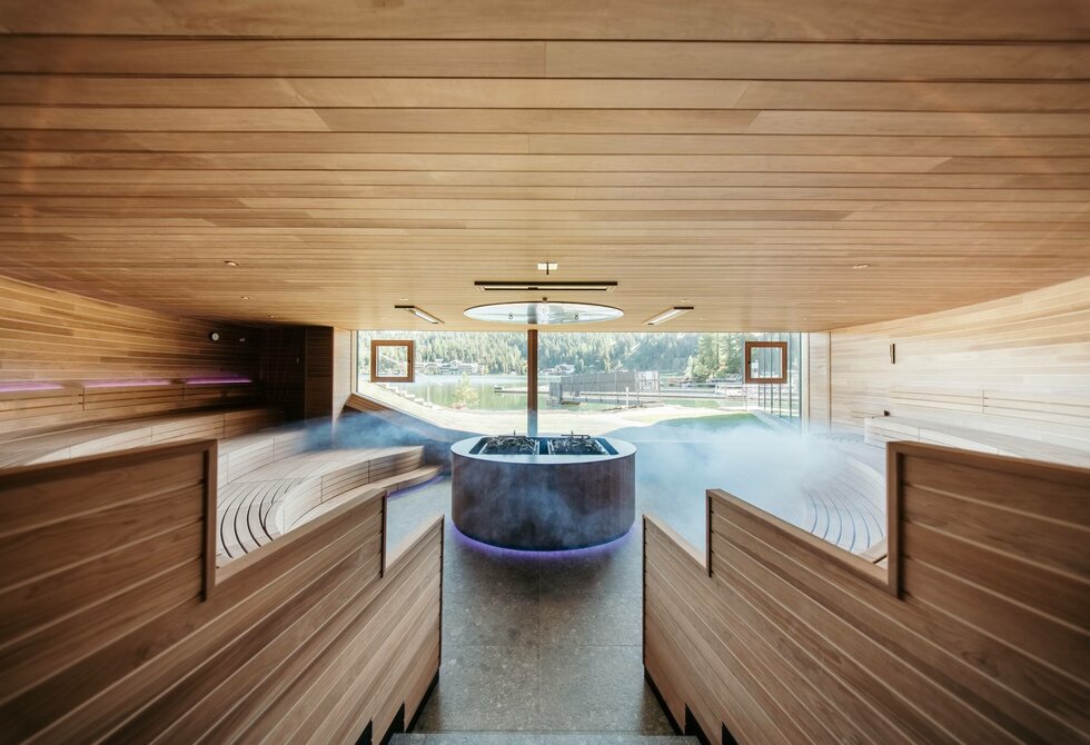 Ein Indoor-Infinitypool mit Holzverkleidung und Blick auf den See im Hotel Hochschober.