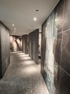 A modern, softly lit corridor with dark stone walls and large-format wall motifs.