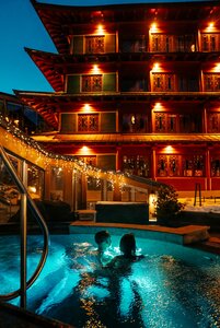 Zwei Personen baden abends im beleuchteten Außenpool vor dem Hotel Hochschober.